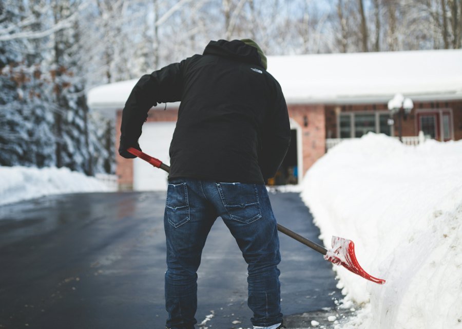 Person räumt Schnee von einer Einfahrt